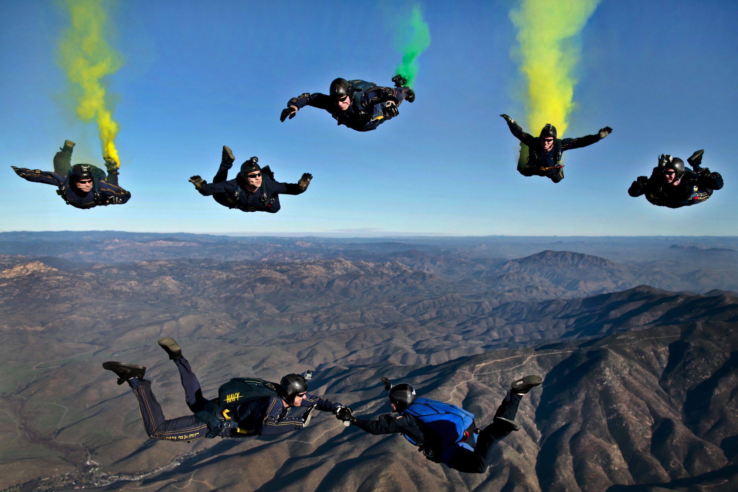 Formation skydiving team in freefall above mountains